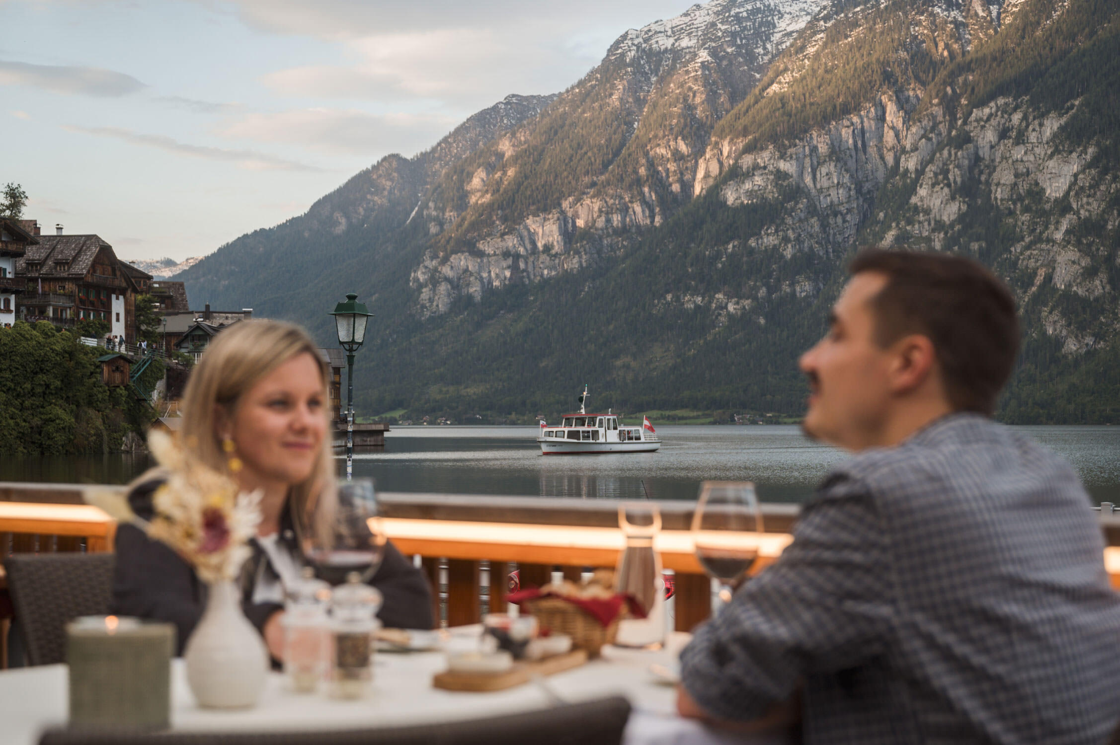 Ein Pärchen, Gäste des Heritage Hotel genießen ihr Abendessen, die Fähre im Hintergrund läuft gerade in Hallstatt ein.